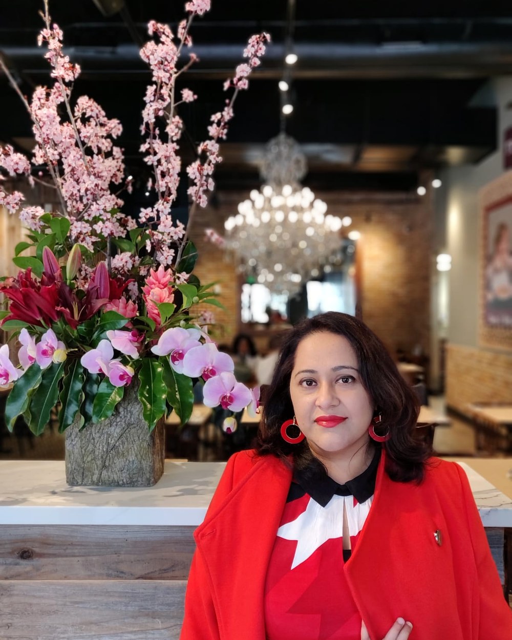 Pankhuri Verma in a red jacket beside a floral display